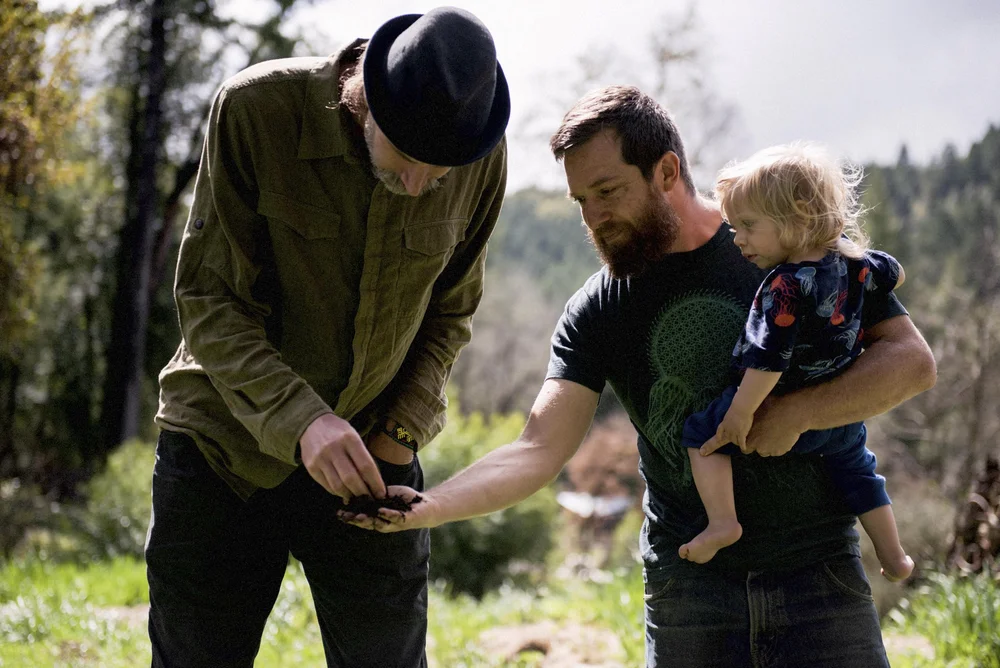 Adult and child crouching together among plants
