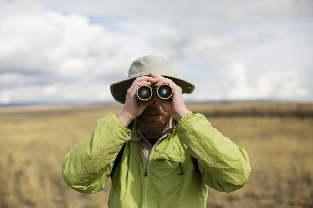 Person using binoculars in open country