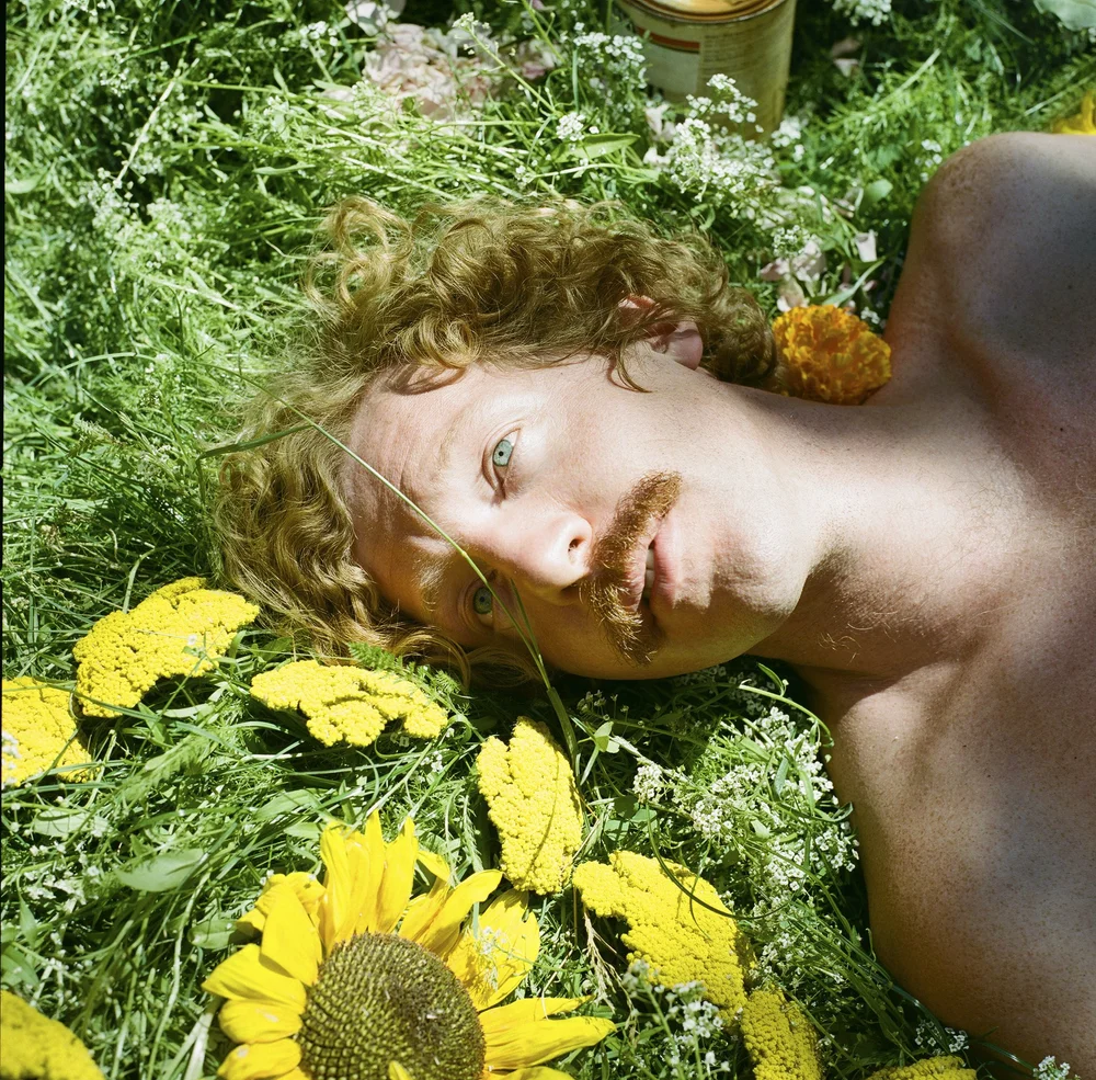 Person resting in grass and yellow flowers