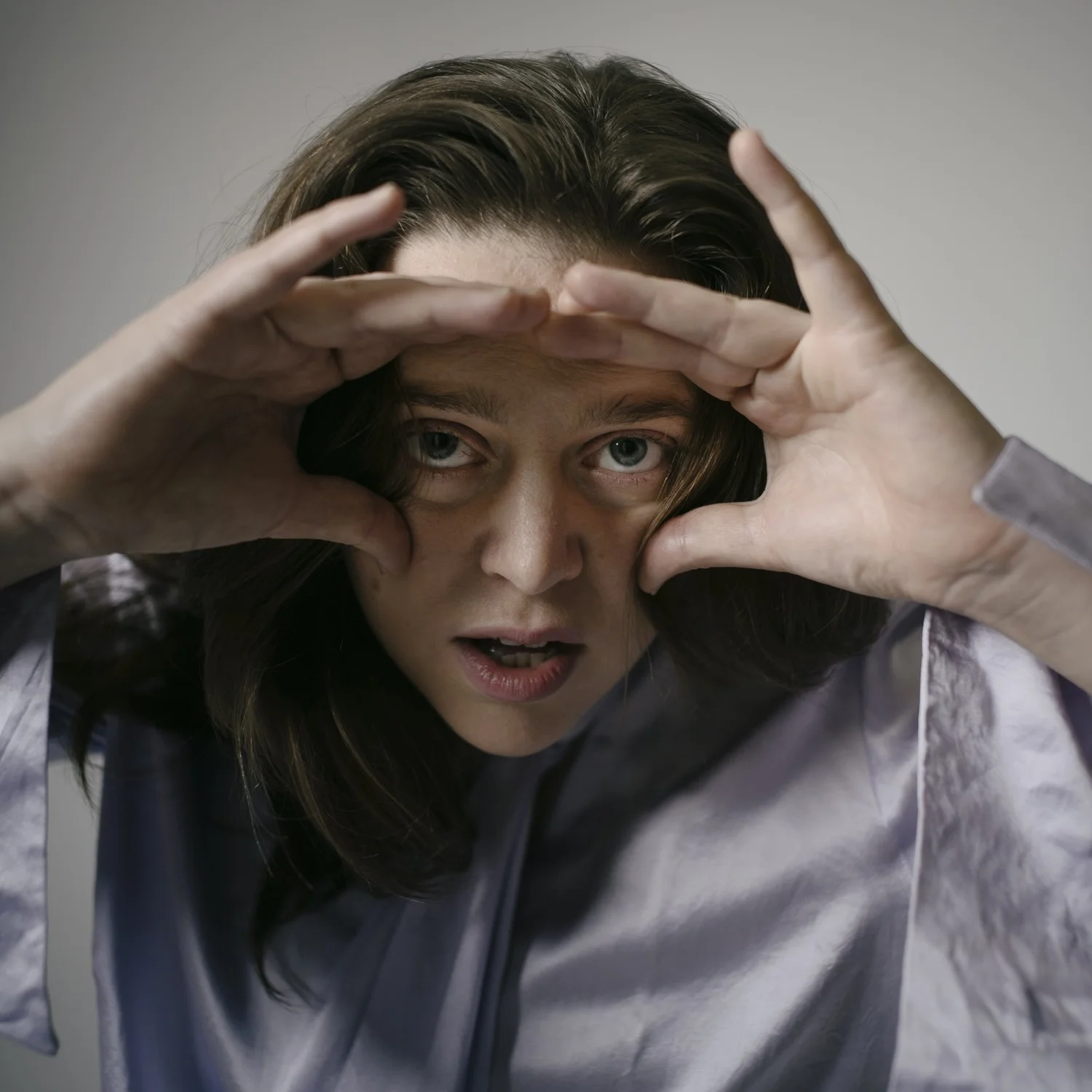 Playful portrait with hands framing the subject’s eyes