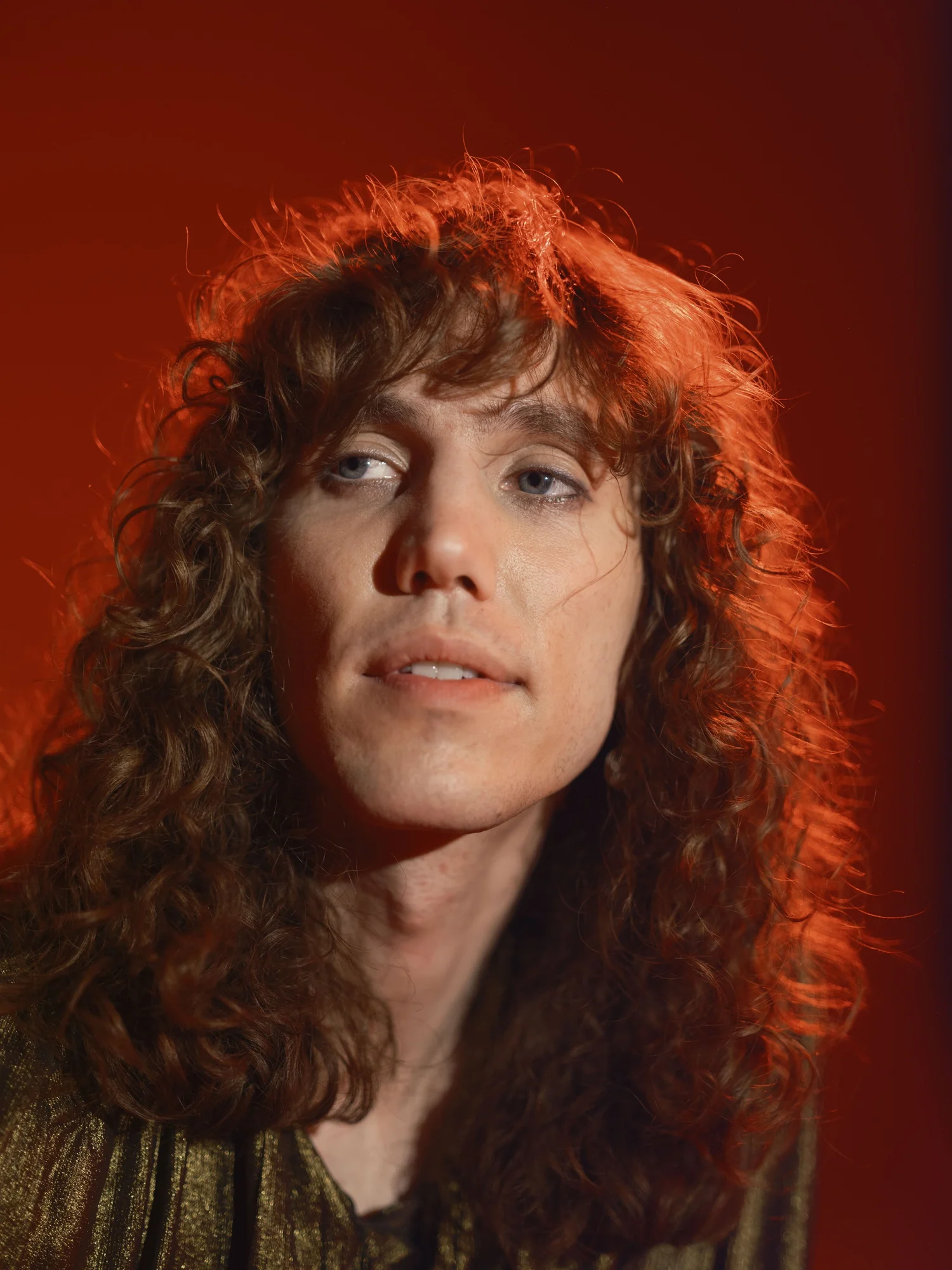 Red-haired woman photographed against deep red