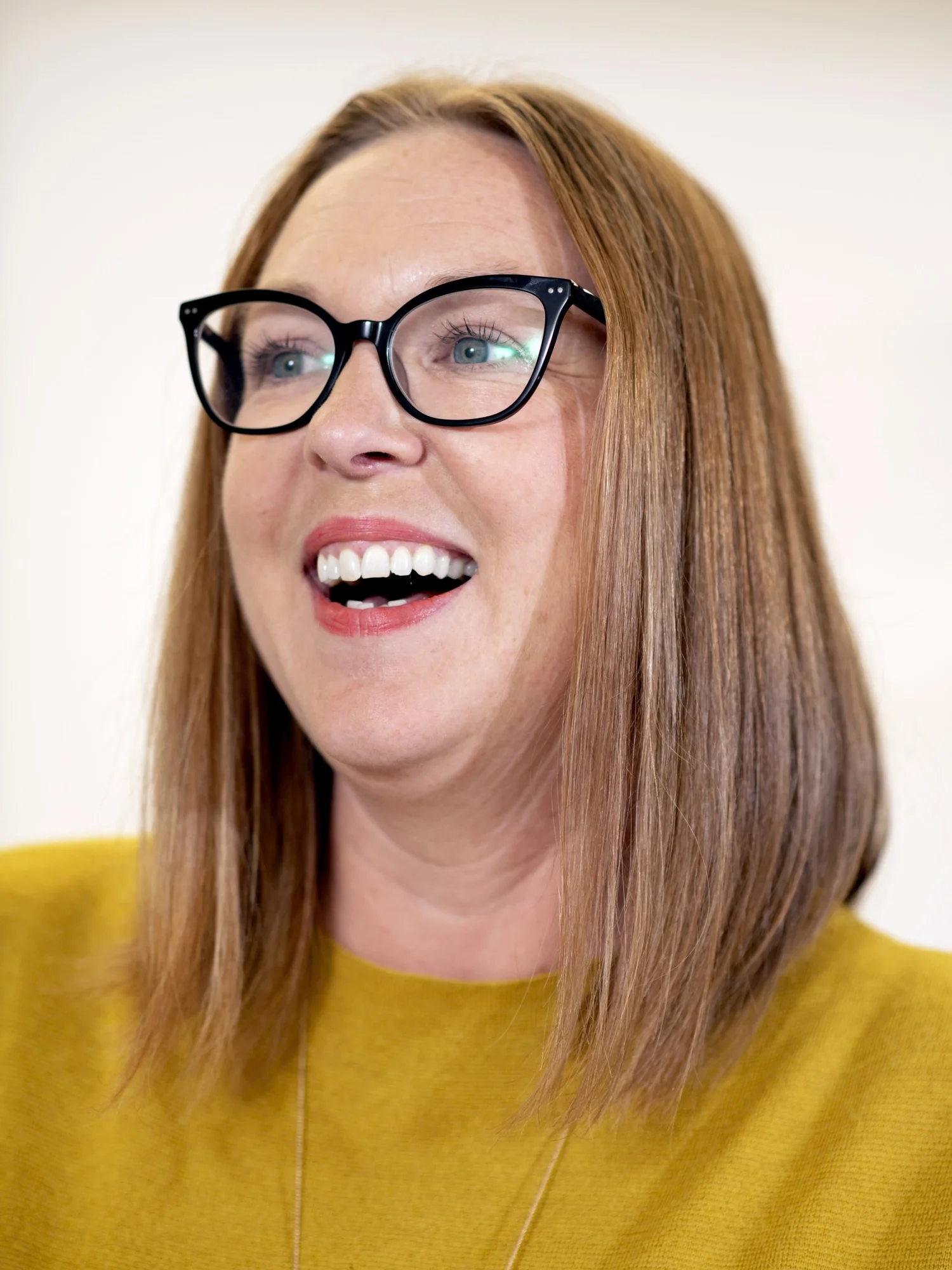 Laughing woman with glasses against yellow