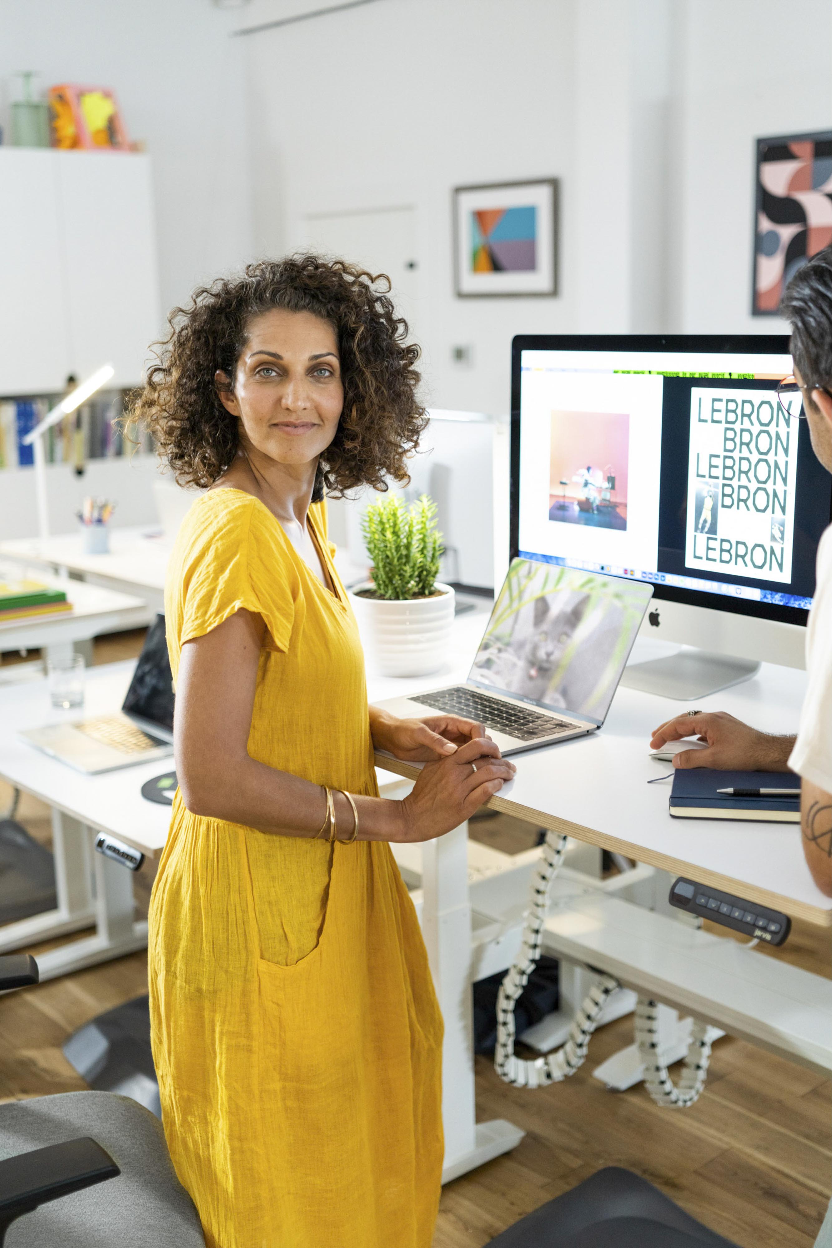 Creative professional in a yellow dress collaborating at a workstation