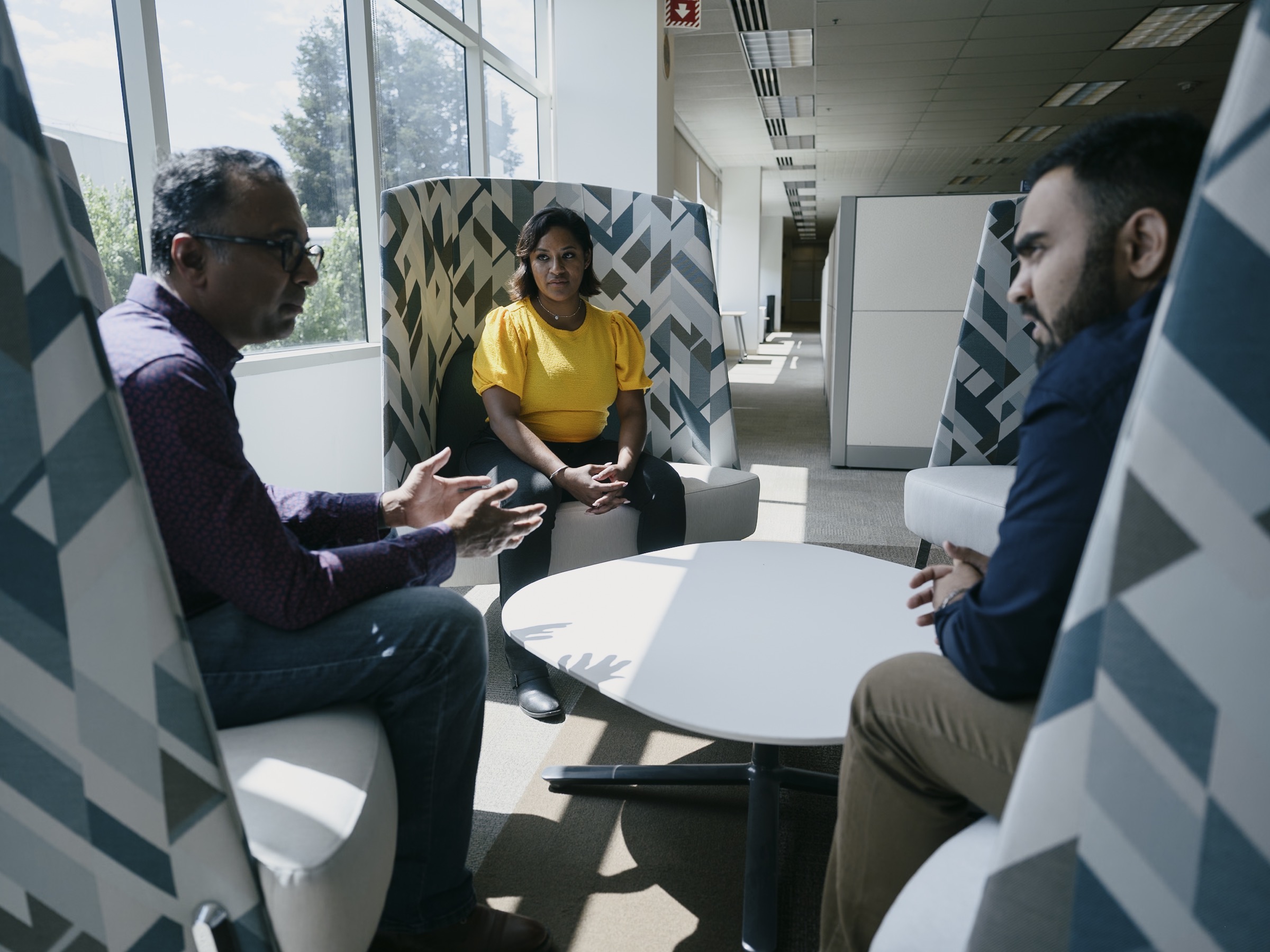 Three colleagues in conversation in a modern workplace