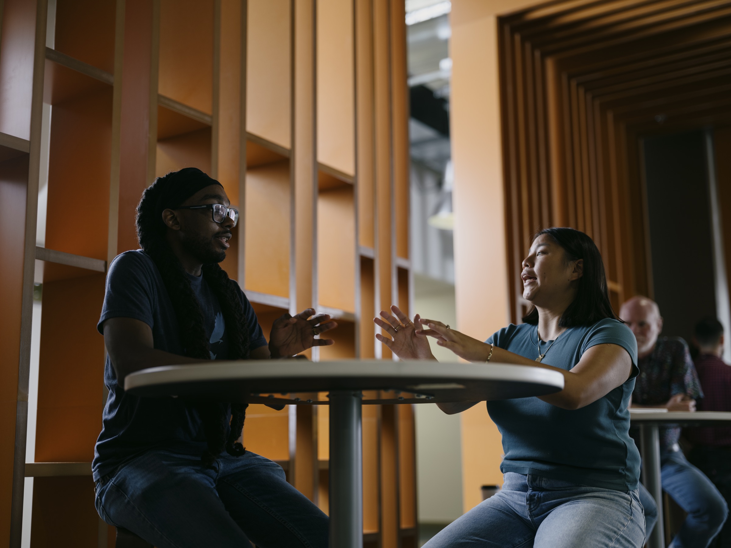 Two colleagues in an animated conversation at a worktable
