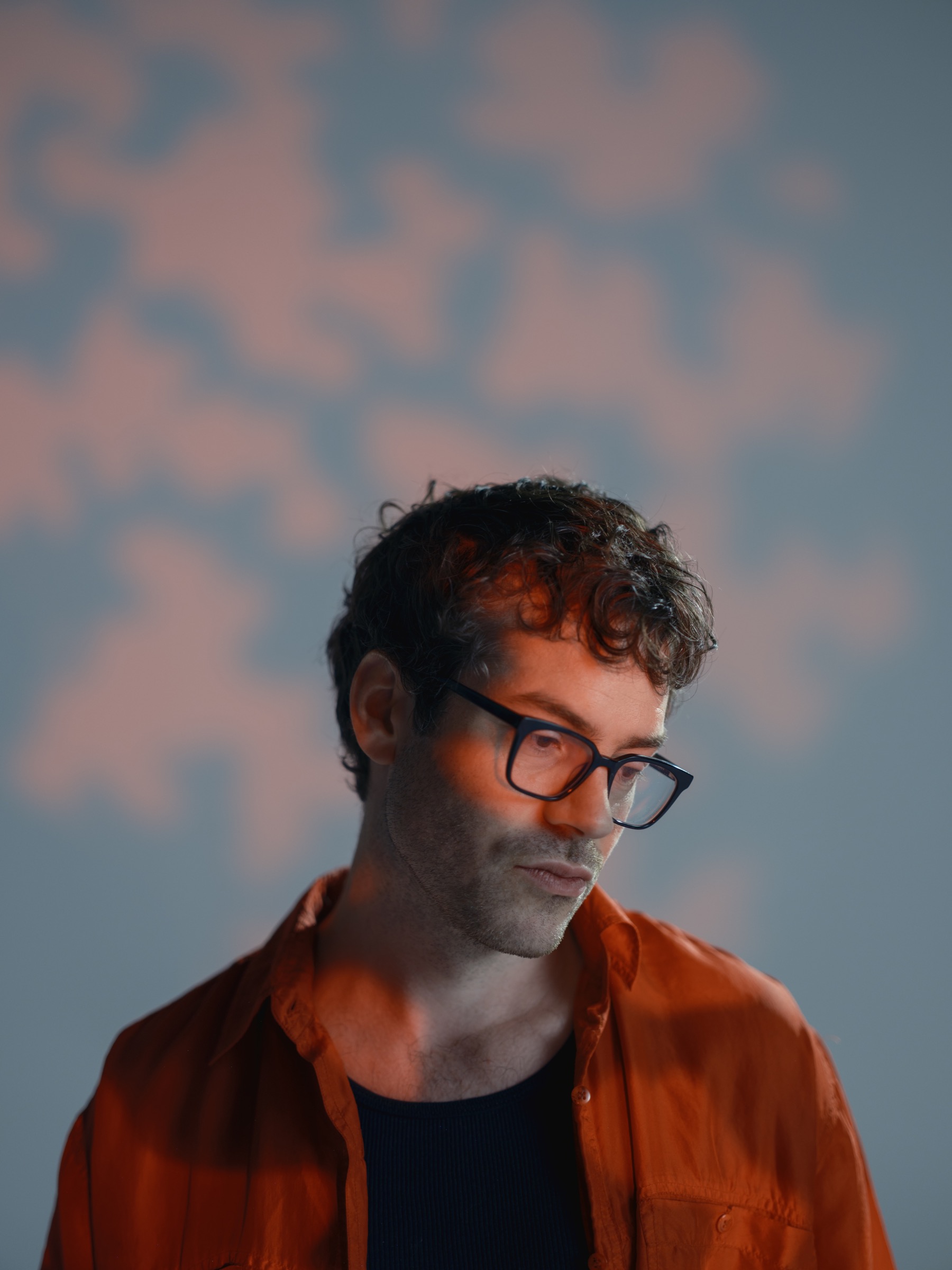 Orange-lit creative portrait of a man wearing glasses