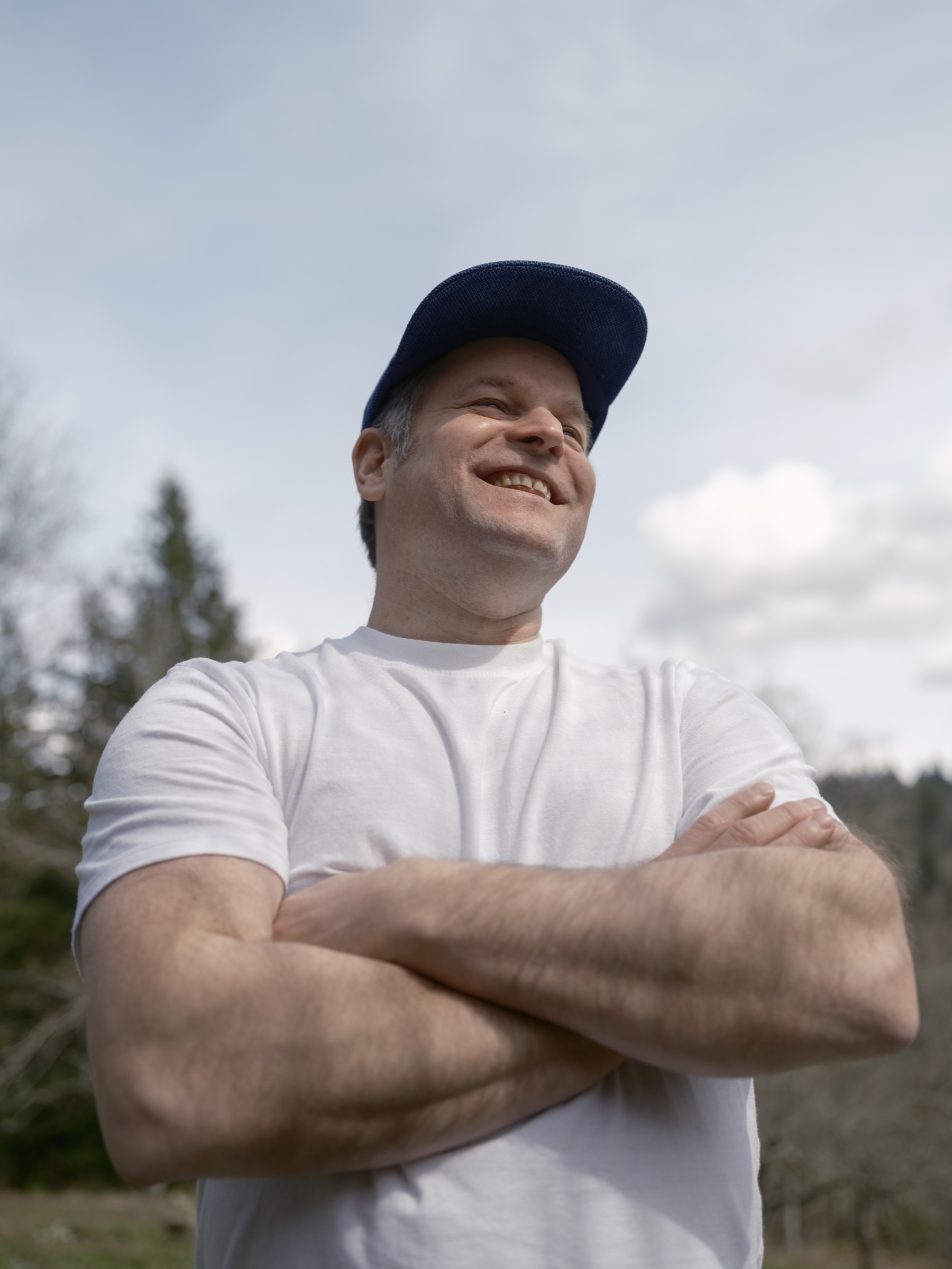 Relaxed outdoor professional portrait of a man in a white shirt and baseball cap