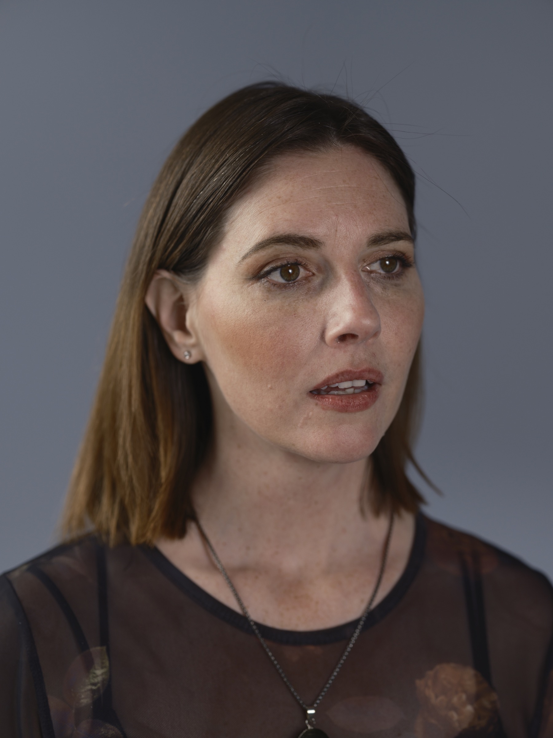 Portrait of a woman looking right against a gray background