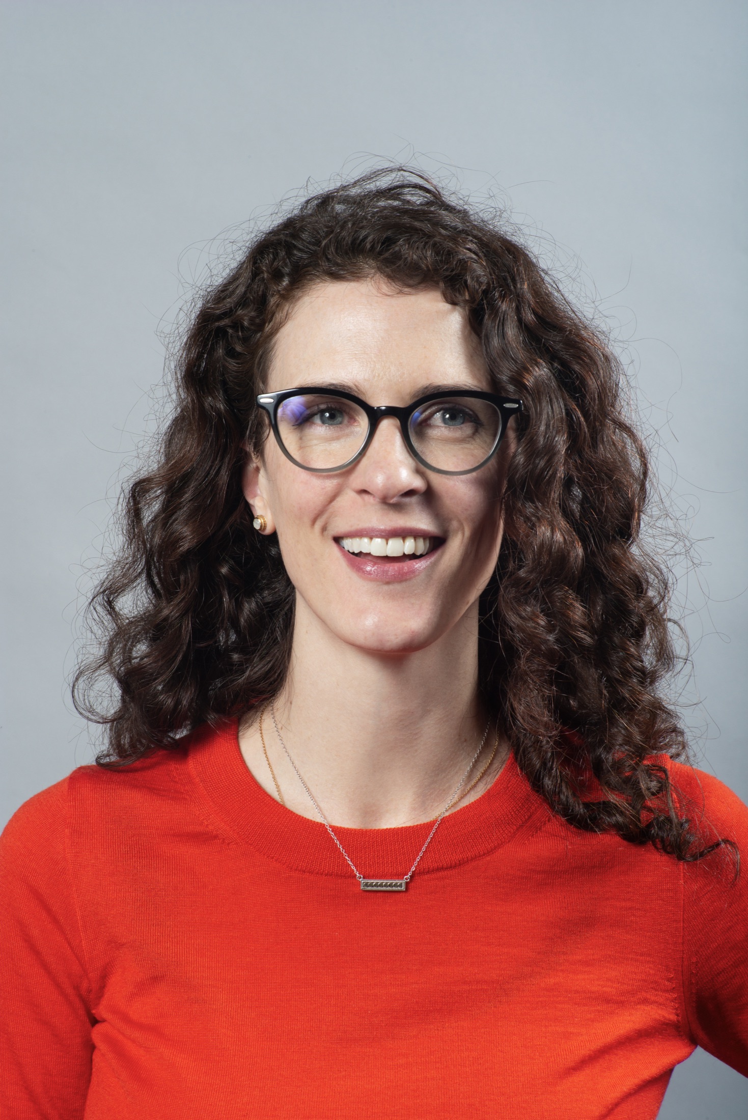Warm professional headshot of a smiling woman with glasses